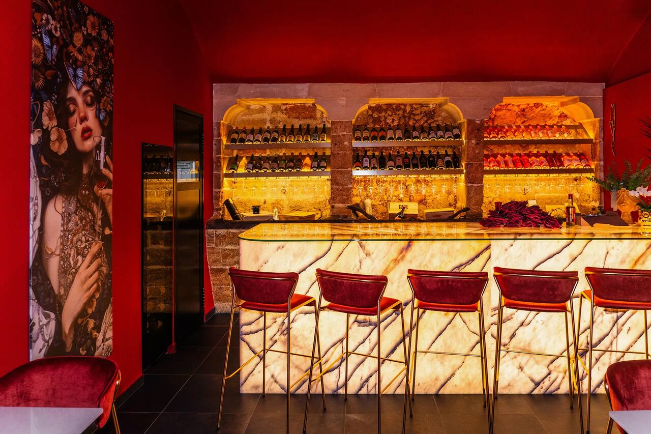 Le nicchie in pietra della sala rossa piene di bottiglie di vino, sopra il bancone in onice