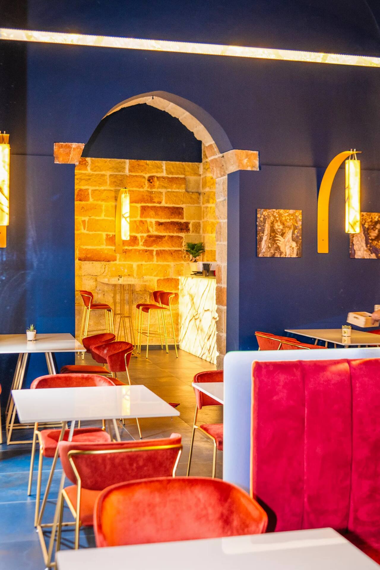 La sala food con i tavoli apparecchiati, le sedute in velluto rosso e l'arco in pietra a sesto acuto