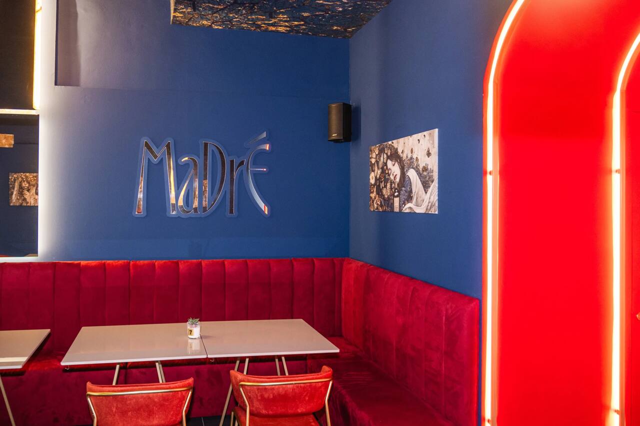 Il lettering Madrè a specchio sulla parete blu, sopra il divano in velluto rosso